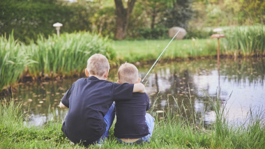 To drenge sidder ved en sø - billedet illustrerer, at teksten henvender sig til børn